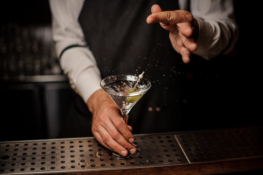 Bartender adding salt into a strong martini cocktail