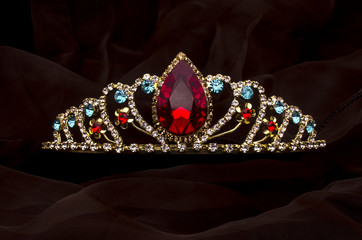 gold diadem with red ruby stone isolated on the fabric