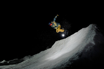 guy in a yellow ski suit jumping on a snowboard