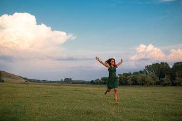 Beautiful young woman running on a meadow at sunset