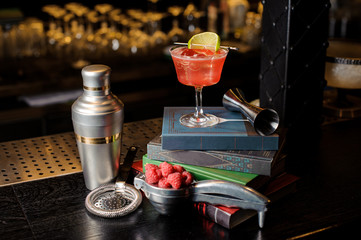 Glass with fresh sweet summer cocktail with lime slice on books