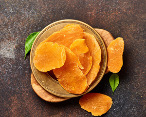 Dried mango slices. Top view of candied fruits on brown background.