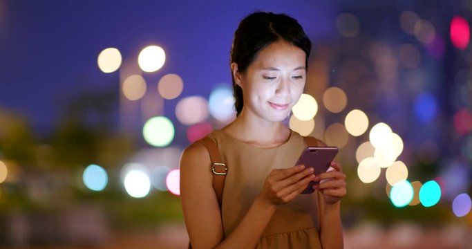 Woman sending text message on mobile phone at night