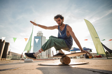 Young man keeping balance on the background of city buildings