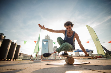 Young smiling man keeping balance on the background of city buildings