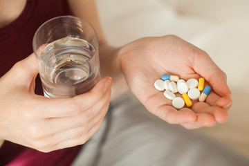 young woman holding pill and glass of water