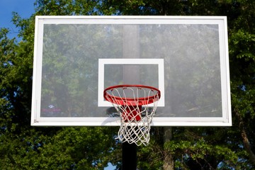 A glass backboard on the outdoors basketball hoop. 