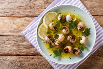 French cuisine: Escargot with butter, herbs and garlic close-up on a plate. Horizontal top view...