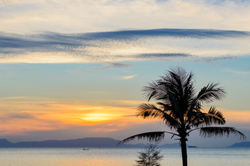 Fototapeta na wymiar Sunset on tropical beach and coconut palm tree and fisherman boat