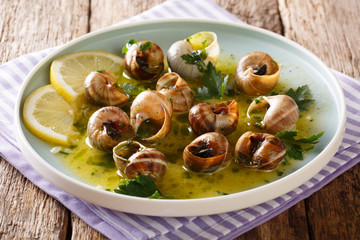 Delicatessen food: edible snails, escargot cooked with butter, parsley, lemon and garlic close-up...