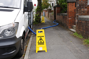 Mobile house cleaning van with caution signs and water pipe