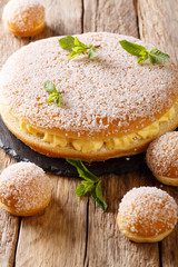 Large and small tropezienne cakes with delicate cream decorated with pearl sugar and mint close-up. vertical
