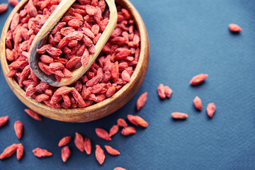 Goji in bowl on wood table. Top view of fresh goji in scoop and bowl. Goji in heart shape on table