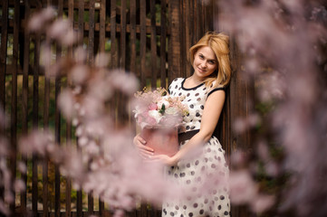 Lovely smiling blonde woman dressed in polka dot dress with a flower box