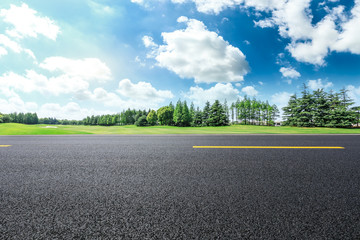 Empty asphalt road and green forest landscape under the blue sky