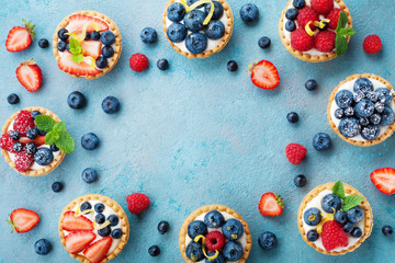 Tasty berry tartlets or cake with cream cheese and different berries around. Pastry dessert top...