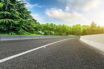 Empty asphalt road and green forest landscape under the blue sky