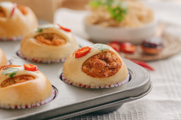 Homemade cup of soft and sticky bun with dried shredded pork or pork floss and shrimp roasted chili paste in muffin tray on wood table. Thai style delicious bread with sweet and spicy taste for snack.