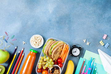 Back to school concept. Healthy lunch box and colorful stationery on blue table top view.