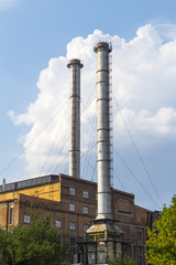 Industrial building with two tall chimneys background on blue sky