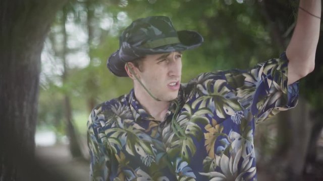 Young Male explorer in Tilly Hat scans the horizon in tropical setting