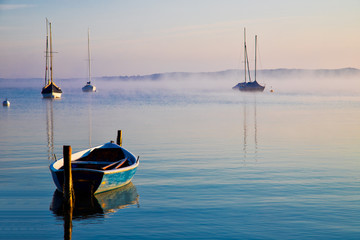 Morgendliche Seelandscahft mit Booten im Nebel
