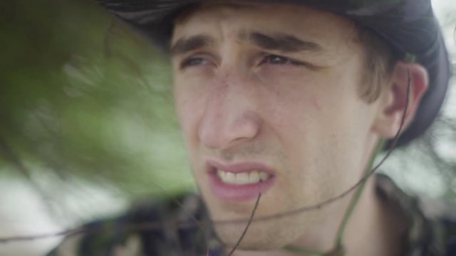 Young man hunting in the forest. Scanning the horizon while hidden in foliage