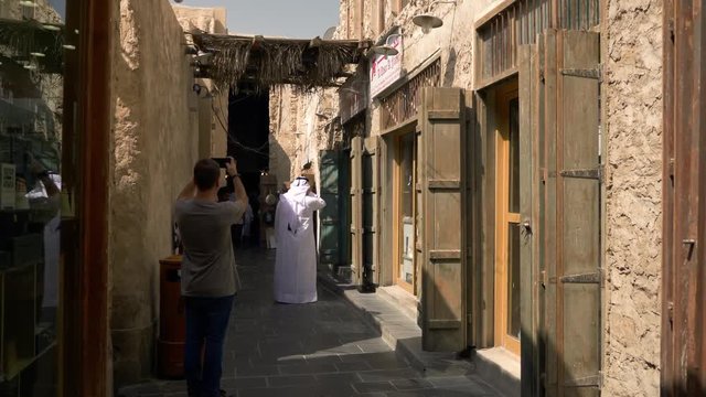 European tourist taking photos with his smartphone in old souq traditional market in middle east Doha Qatar.