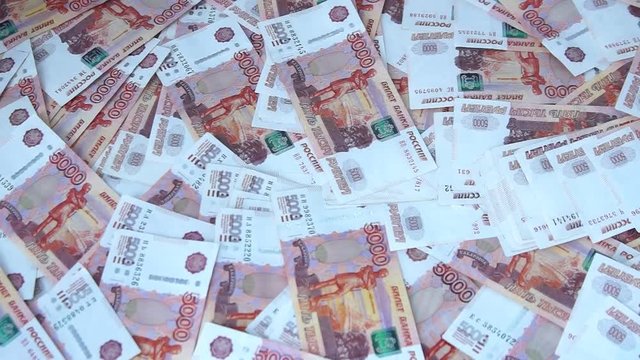 Many Russian banknotes of 5000 rubles are on the table. Background made of money