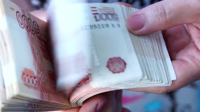 Woman leafing through a thick pack of Russian banknotes in denominations of 5000 rubles