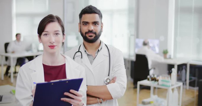 Chief doctor male and female nurse with folder standing together and looking at camera. Portrait professional doctors of modern gynecological clinic