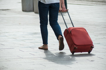 closeup of woman walking  in the street with suitcase near the train station