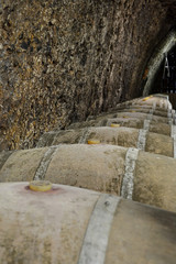 Old wooden barrels with wine in a wine vault, aged traditional wooden barrels up in cool and dark cellar,