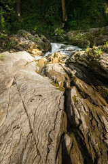 Fototapeta na wymiar Wide angle shot of mountain river with a waterfall flowing between rocky coasts. Expressive foreground. Taken from low point of view at sunny spring day at Carpathian mountains. Natural background. 