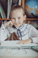 A little schoolgirl sits at a desk