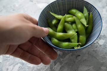 Frau isst Portion grüne, japanische Edamame Sojabohnen in Porzellan Schale