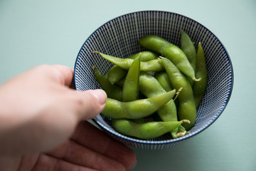 Frau isst Portion grüne, japanische Edamame Sojabohnen in Porzellan Schale