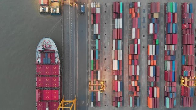 Aerial view over industrial import or export port of Thailand in Bangkok with many rows and stacks of container and big container loader ship vessel.