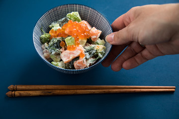Frau serviert rohes Lachs Avocado Tatar mit Keta Kaviar und Holz Stäbchen