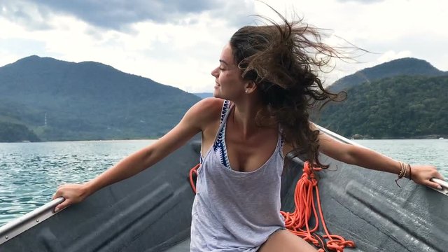 Happy pretty girl having a ride on a boat on the ocean, Ubatuba Brazil