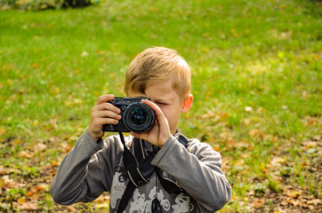 The boy is a photographer in the park.