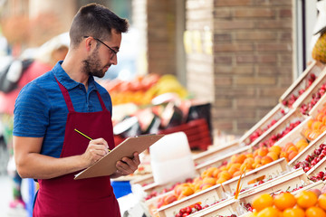 Handsome young salesman doing inventory in health grocery shop.
