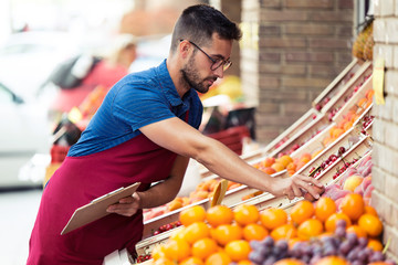 Handsome young salesman doing inventory in health grocery shop.