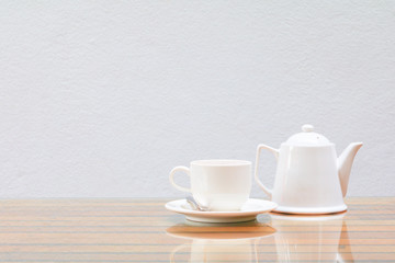 Fototapeta na wymiar coffee cup and teapot white On the glass table wooden and a cement wall background. copy space