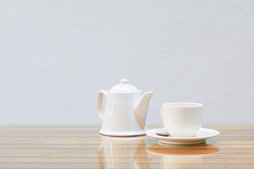 coffee cup and teapot white On the glass table wooden and a cement wall background. copy space