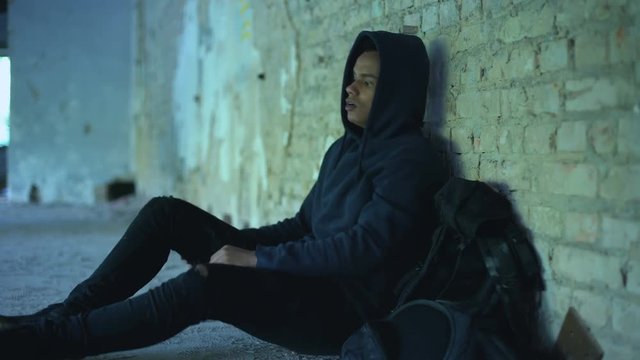 Afro-american teenager hiding from bullying in abandoned building, racism