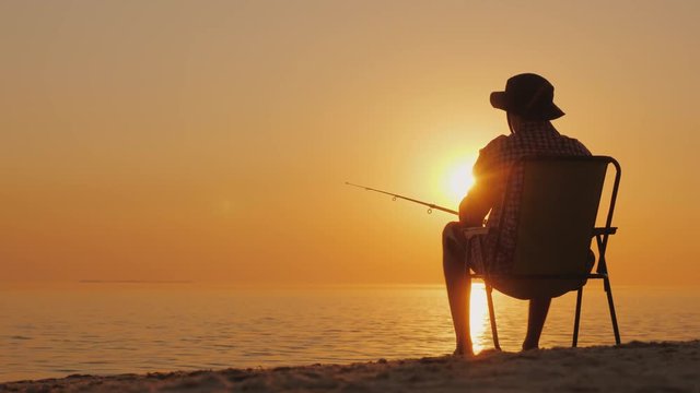 A young man is sitting on the seashore, fishing. Relaxing in the open air