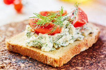 Vegetarian breakfast of champions. Sandwich with egg paste with dill on toasted bread. Tomatoes cocktail and a sprig of fresh, green dill on top on top.