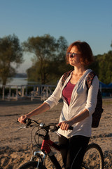 A girl with a bike on a beach in the summer morning