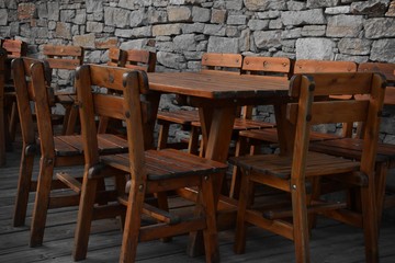 Tables and chairs of wood near the stone wall
